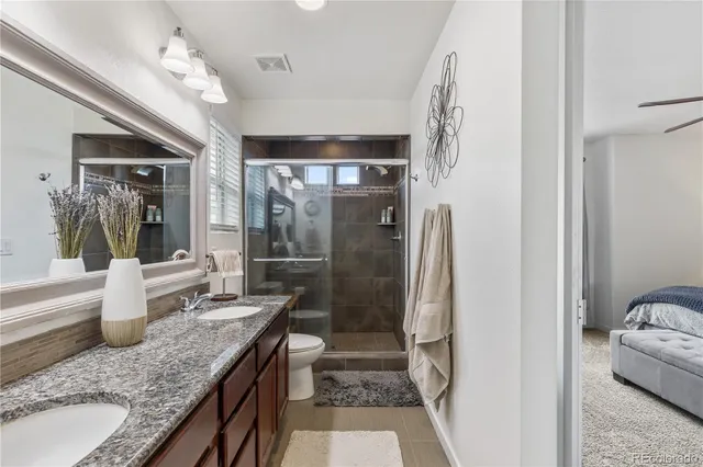 a bathroom with a granite countertop sink a toilet and shower
