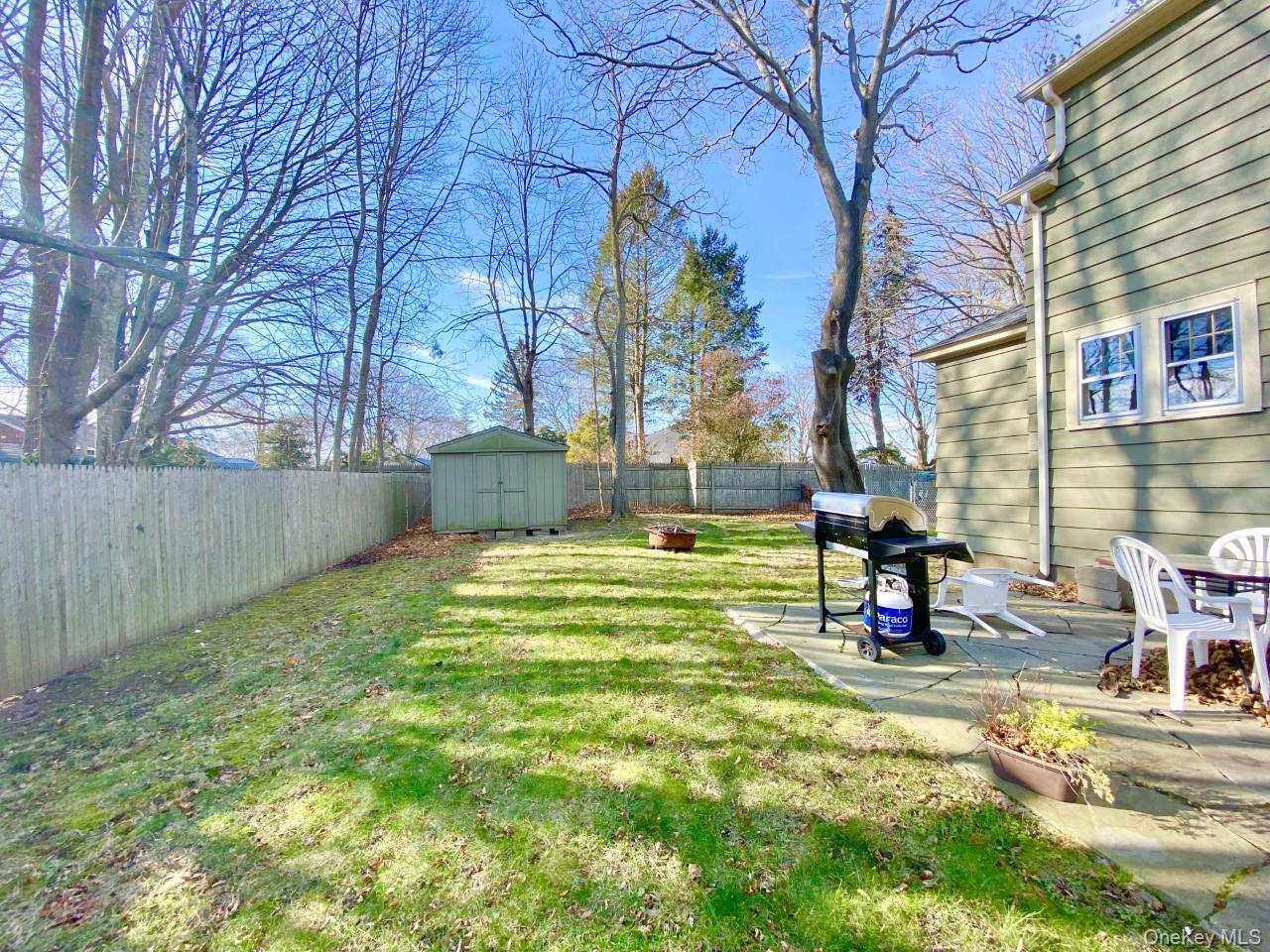 2490 Pike Street Mattituck, NY 11952 - Photo 15 of 15 Fenced backyard featuring a patio area, a storage unit, and an outdoor fire pit