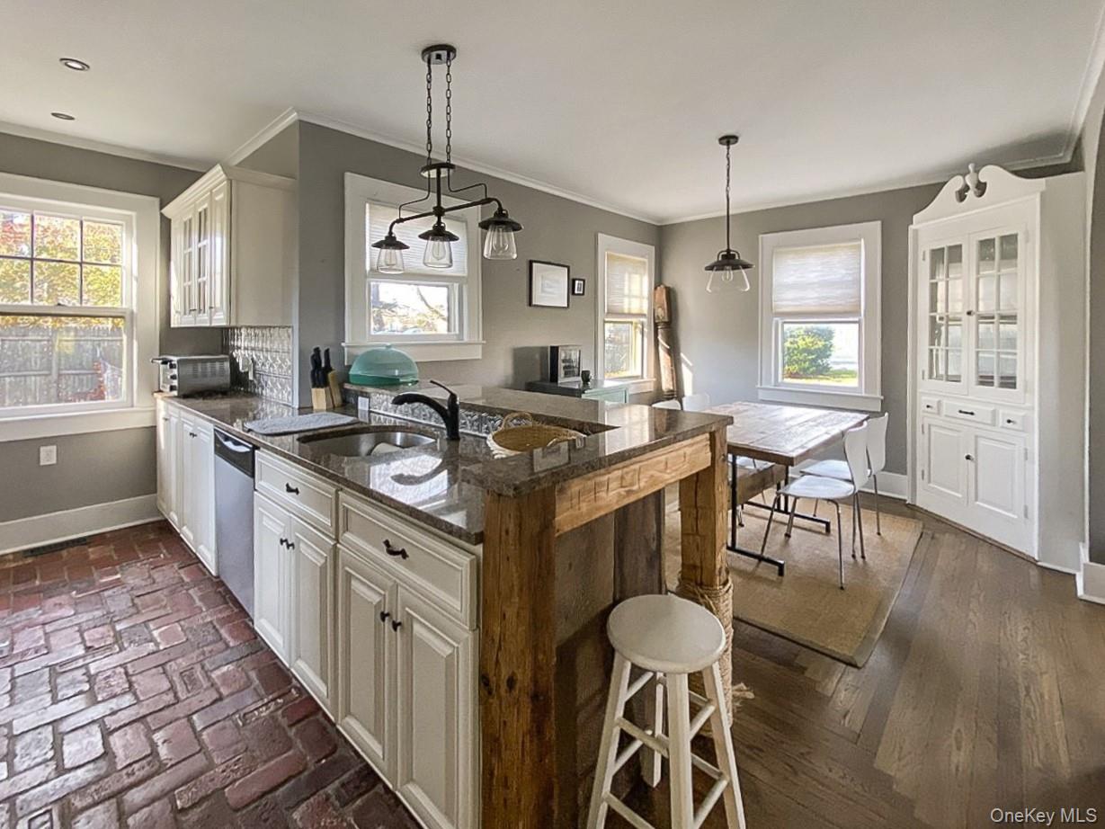 2490 Pike Street Mattituck, NY 11952 - Photo 5 of 15 Kitchen with a kitchen bar, decorative light fixtures, a peninsula, dark stone counters, and crown molding
