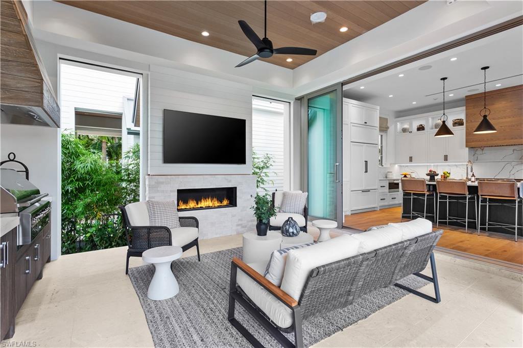 835 11th Avenue South Naples, FL 34102 - Photo 11 of 31 a living room with furniture a fireplace and a flat screen tv