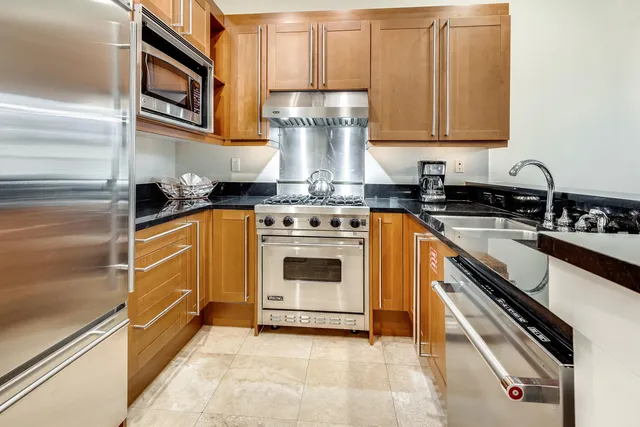 a kitchen with granite countertop stainless steel appliances a stove top oven and sink