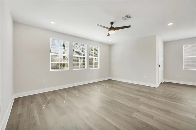 a view of empty room with wooden floor and windows