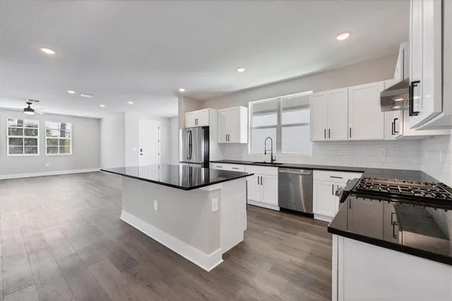 a kitchen with stainless steel appliances granite countertop a sink and a stove top oven with wooden floor
