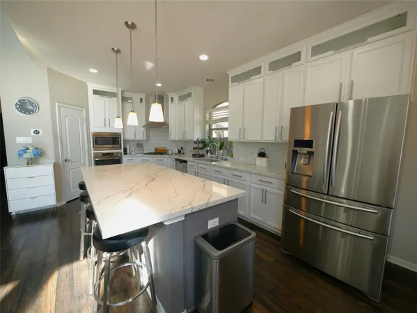 a kitchen with stainless steel appliances granite countertop a refrigerator a sink a stove and a refrigerator