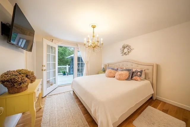 a bedroom with a bed potted plant on dresser and a chandelier