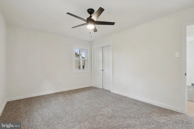 an empty room with a chandelier fan and windows