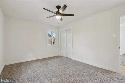 an empty room with a chandelier fan and windows