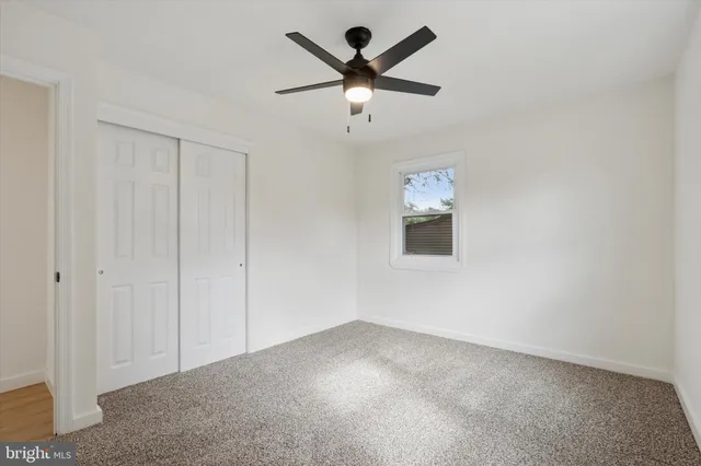 an empty room with ceiling fan and window