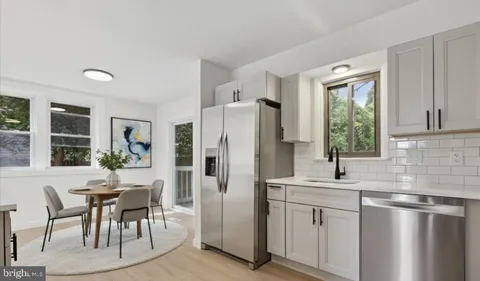 a kitchen with stainless steel appliances granite countertop a refrigerator a sink a stove and white cabinets