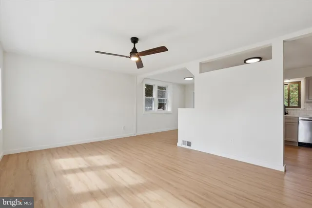 a view of empty room with wooden floor and ceiling fan