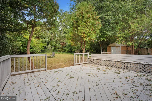 a view of wooden deck and a lake with trees in the background