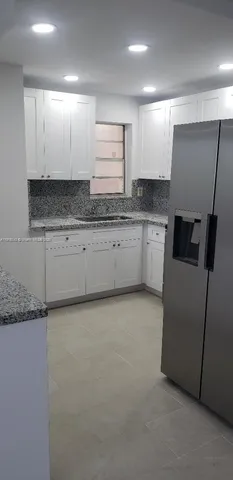 a kitchen with granite countertop white cabinets and white appliances