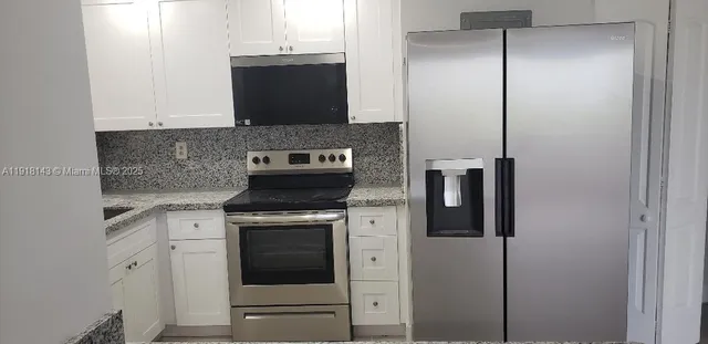 a kitchen with stainless steel appliances white cabinets and a refrigerator