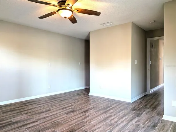 an empty room with wooden floor closet and windows