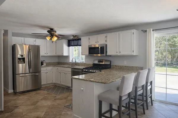 a kitchen with granite countertop a stove a sink and a refrigerator