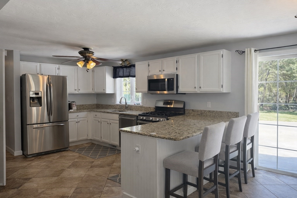 11 Trout Farm Way Wareham, MA 02576 - Photo 7 of 24 a kitchen with stainless steel appliances granite countertop a refrigerator a stove a sink a dining table and chairs