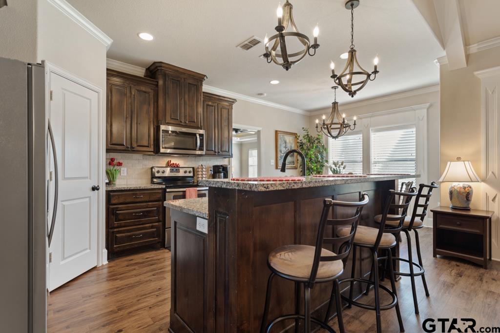 706 Duke Place Tyler, TX 75704 - Photo 8 of 33 a kitchen with stainless steel appliances granite countertop a refrigerator a stove a kitchen island a dining table and chairs with wooden floor