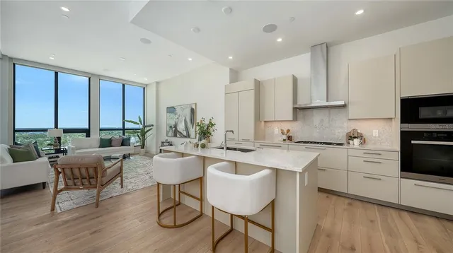 a kitchen with stainless steel appliances granite countertop a stove top oven a sink dishwasher and white cabinets with wooden floor