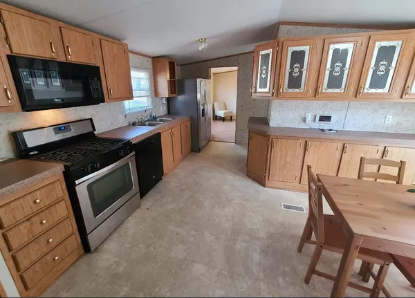 a kitchen with stainless steel appliances kitchen island granite countertop a stove top oven a sink a dining table and chairs