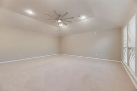 an empty room with a window and chandelier fan