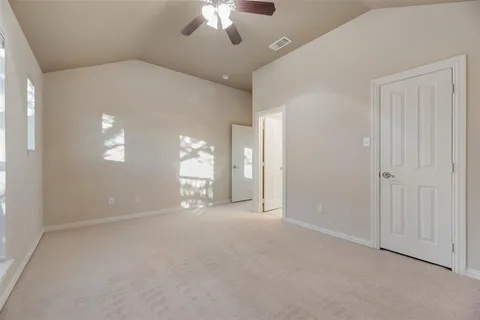 an empty room with chandelier fan and windows