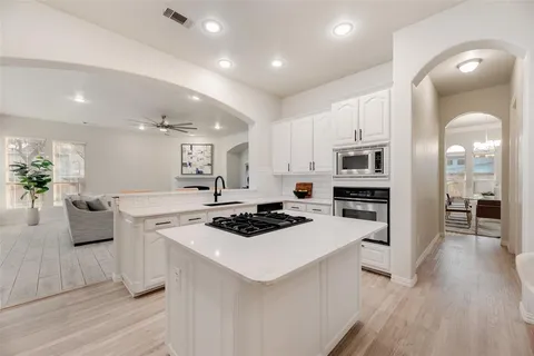 a kitchen with stainless steel appliances a white stove top oven a sink dishwasher and a refrigerator with wooden floor