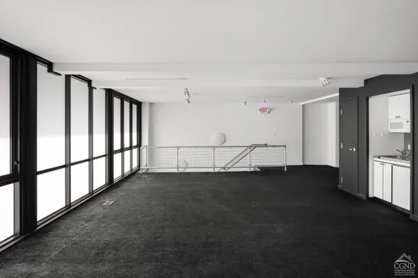 a view of an empty room with chandelier fan and wooden floor