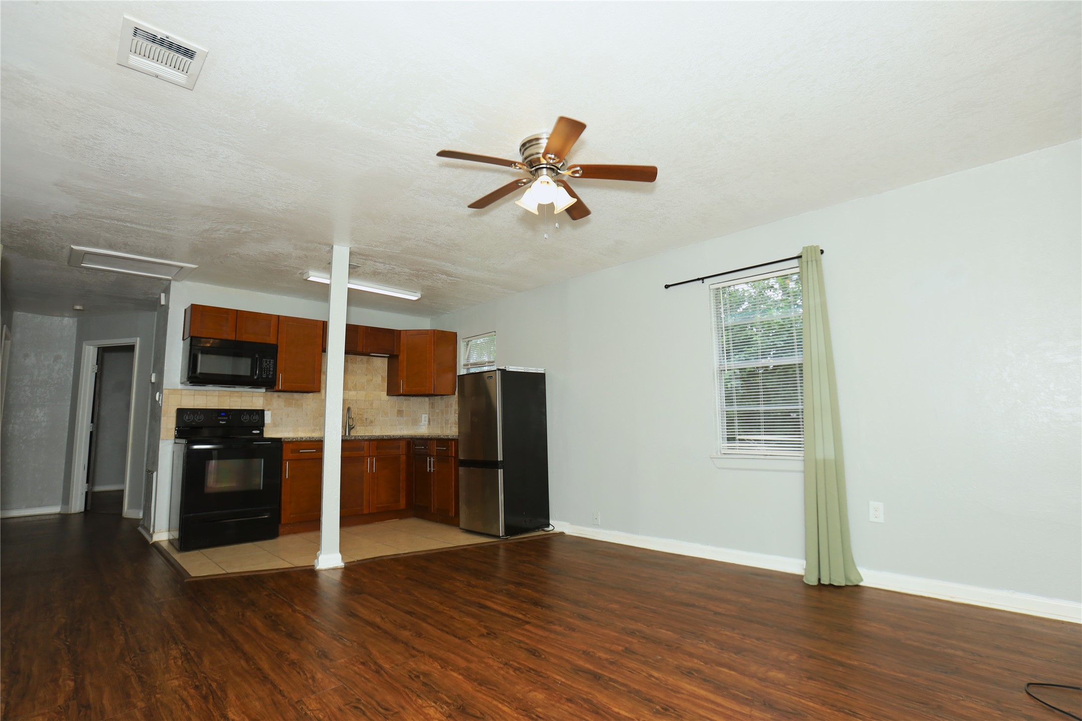 713 South Valderas Street Angleton, TX 77515 - Photo 2 of 10 an empty room with wooden floor ceiling fan and windows