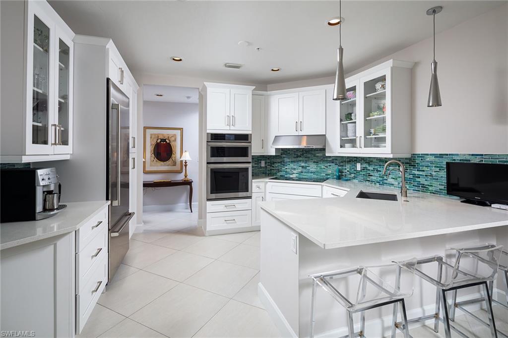 142 Colonade Circle Naples, FL 34103 - Photo 3 of 30 a kitchen with stainless steel appliances a stove a sink a microwave a dining table and chairs