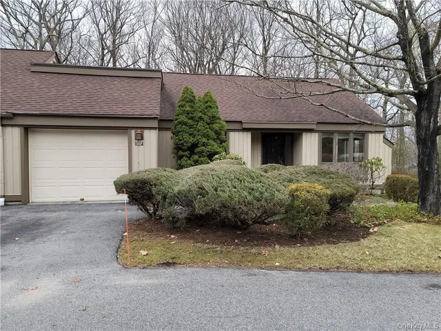 a view of a house with a yard plants and large tree