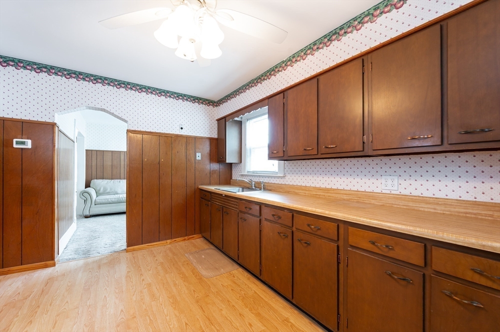 86 Epping Street Lowell, MA 01852 - Photo 5 of 41 a kitchen with stainless steel appliances granite countertop a refrigerator a sink dishwasher and wooden cabinets with wooden floor
