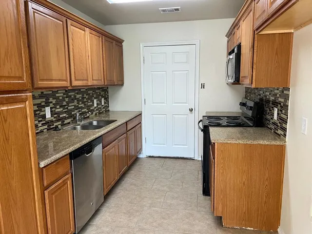 a kitchen with stainless steel appliances granite countertop a stove a sink and a microwave