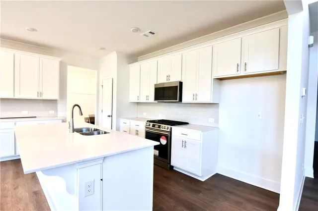 a kitchen with stainless steel appliances granite countertop a sink a stove a microwave and cabinets