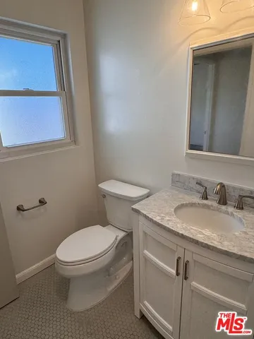 a bathroom with a granite countertop toilet a sink and a mirror