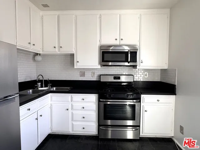 a kitchen with granite countertop white cabinets and stainless steel appliances