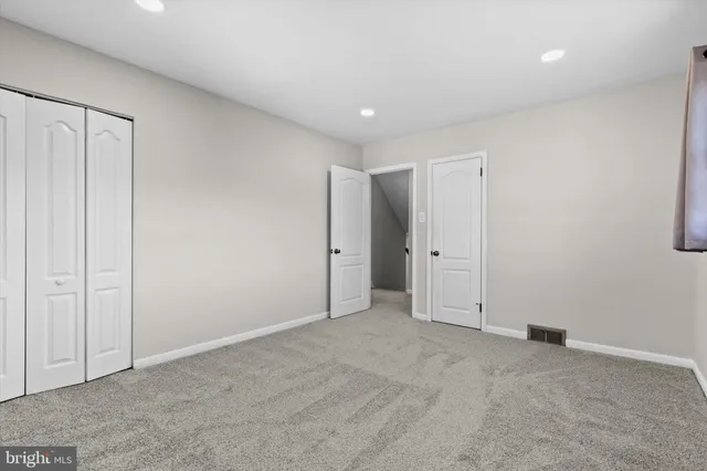 a view of an empty room with closet and a window