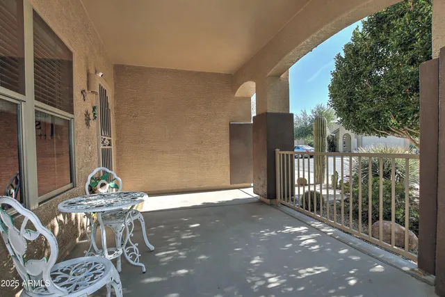 a view of a patio with table and chairs and floor to ceiling window and trees
