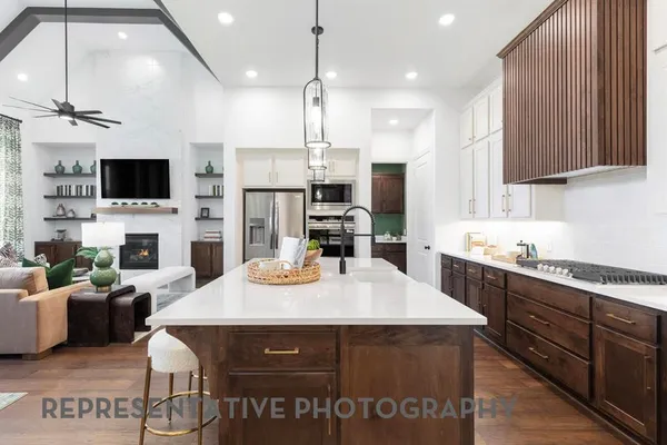 a open kitchen with stainless steel appliances granite countertop a stove a refrigerator a kitchen island a sink dishwasher a dining table and chairs with wooden floor