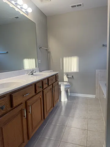a spacious bathroom with a granite countertop sink a toilet and a mirror