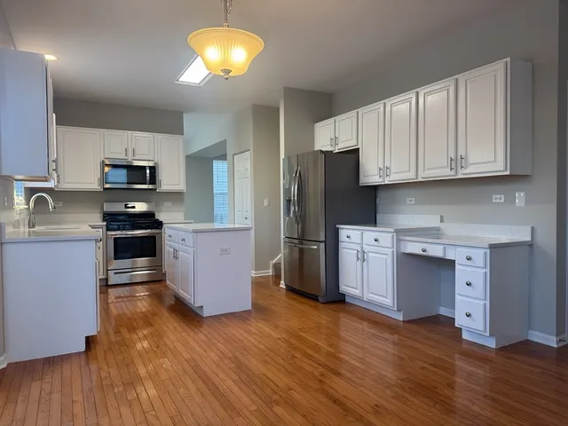 a kitchen with granite countertop wooden floors stainless steel appliances and sink