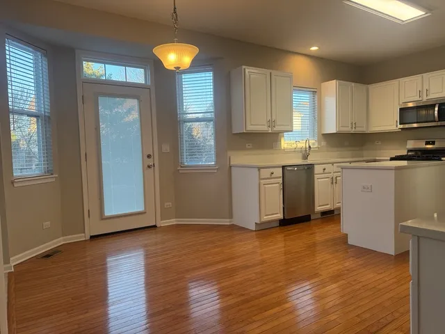 a kitchen with stainless steel appliances granite countertop a stove a sink and white cabinets with wooden floor