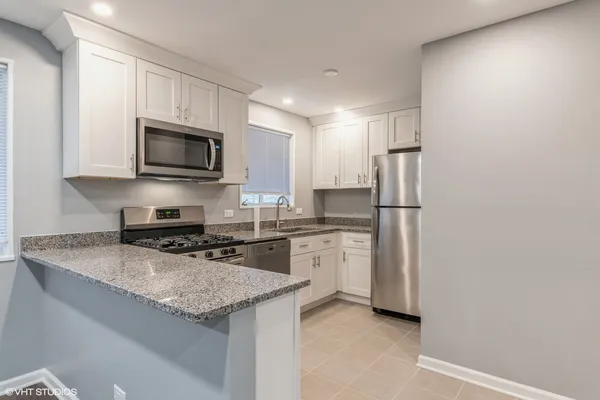 a kitchen with refrigerator a microwave a sink and cabinets