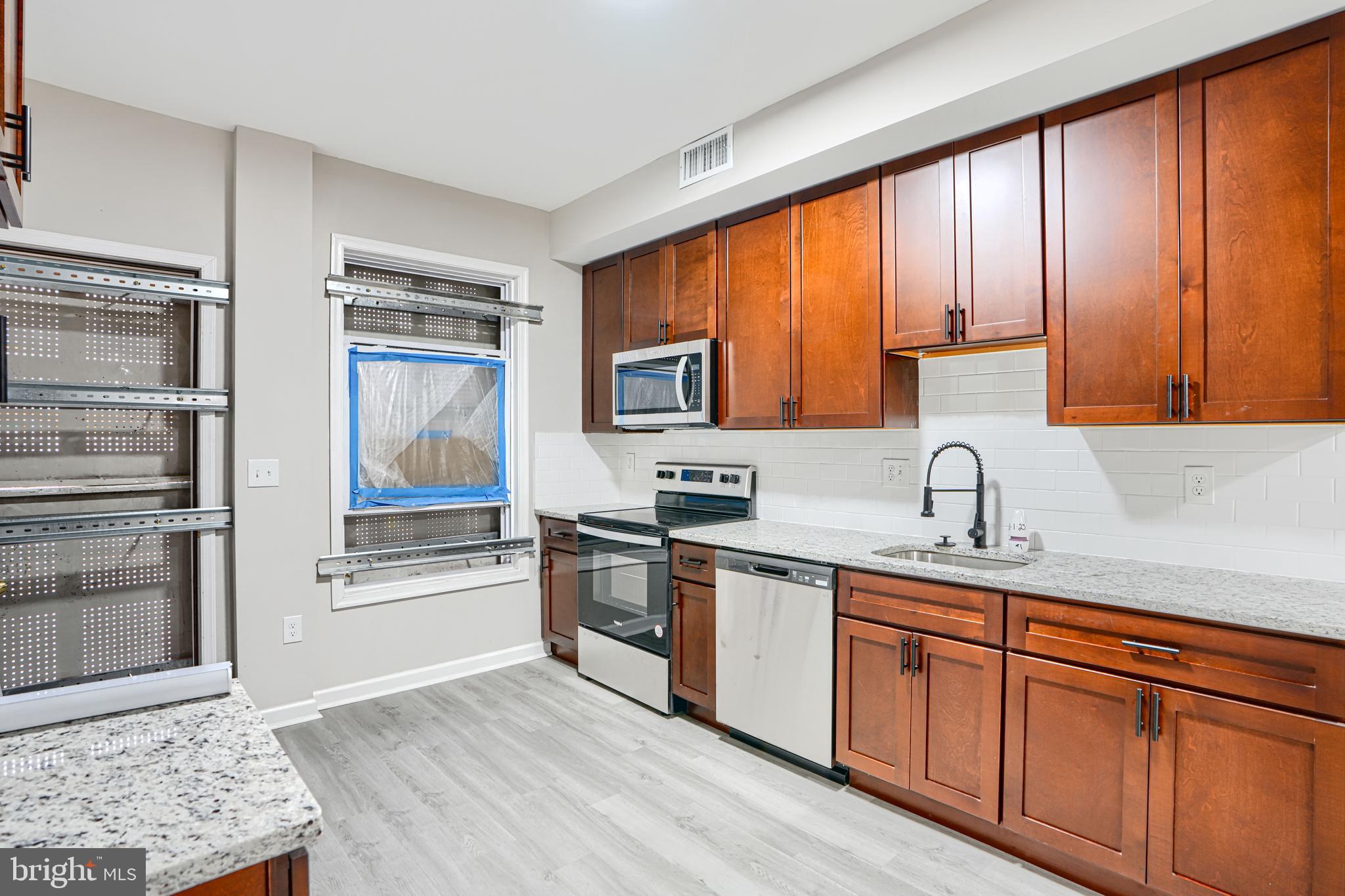 717 North Streeper Street Baltimore, MD 21205 - Photo 8 of 29 a kitchen with stainless steel appliances granite countertop wooden cabinets a sink and a window