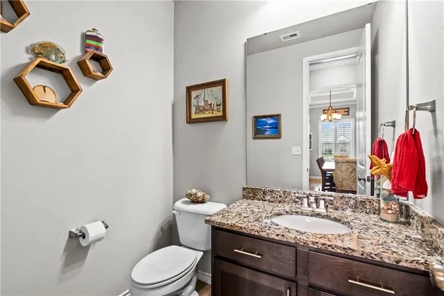 a bathroom with a granite countertop toilet sink and mirror