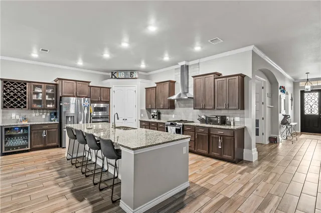 a kitchen with stainless steel appliances a stove a sink a refrigerator white cabinets and wooden floor