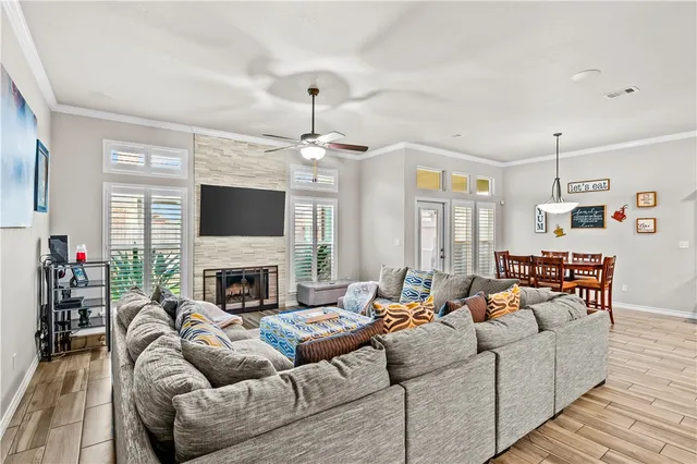 a living room with furniture a fireplace and a dining table with wooden floor
