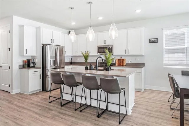 a kitchen with stainless steel appliances kitchen island granite countertop a dining table chairs refrigerator and sink