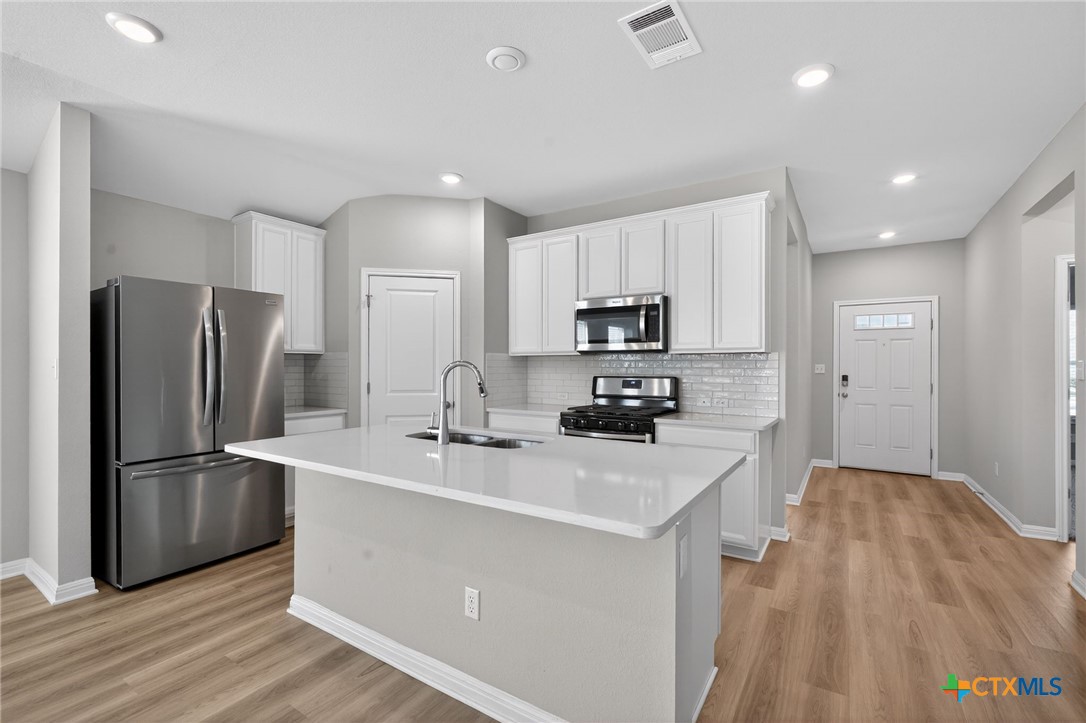 900 Main Street Hutto, TX 78634 - Photo 3 of 23 a kitchen with stainless steel appliances a refrigerator sink and microwave