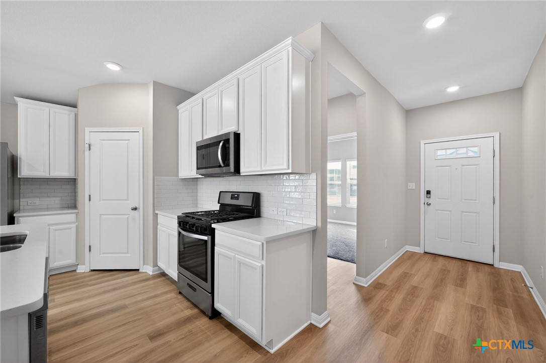 900 Main Street Hutto, TX 78634 - Photo 6 of 23 a kitchen with white cabinets and stainless steel appliances