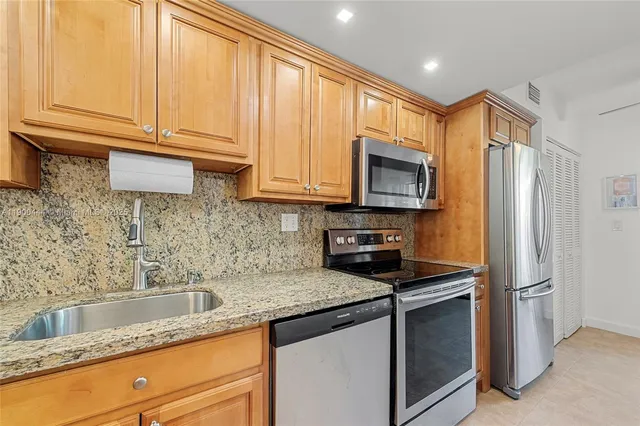 a kitchen with granite countertop a sink stainless steel appliances and cabinets